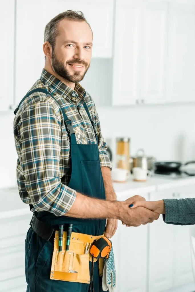 smiling-handsome-plumber-and-customer-shaking-hands-in-kitchen
