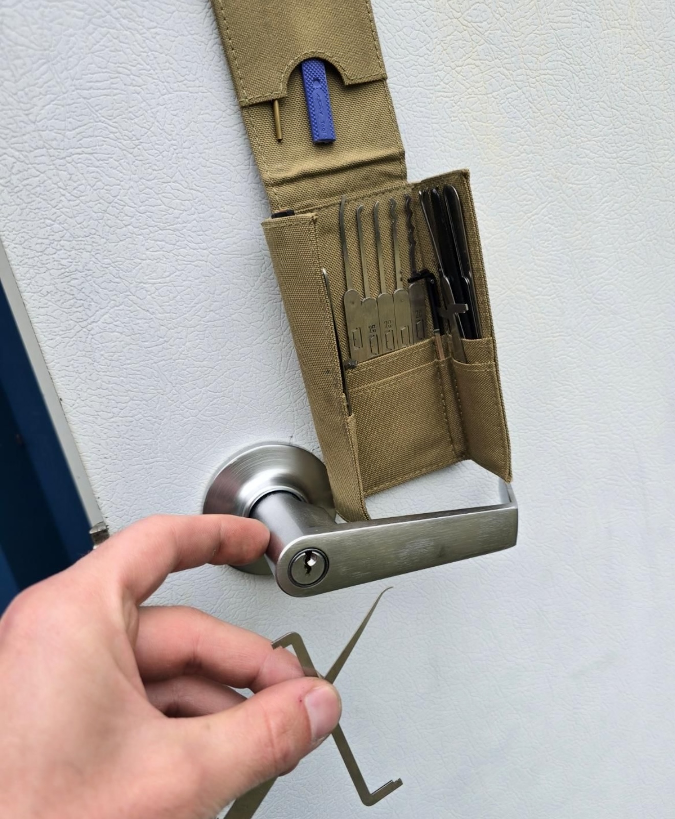 Hand with lock pick near door handle, lockpick tools pouch visible, showing expert Residential Locksmith Service