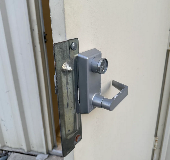 A close-up of a metal door handle on a door, featuring an electric strike mechanism for secure access.