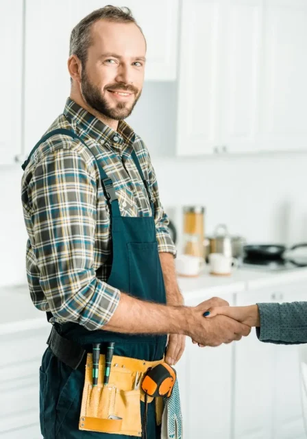 smiling-handsome-plumber-and-customer-shaking-hands-in-kitchen (1)