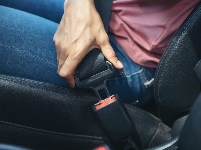 woman hand fastening a seatbelt in the car, Cropped image of a w woman hand fastening a seatbelt in the car, Cropped image of a woman sitting in car and putting on her seat belt, Safe driving concept.